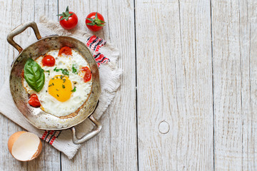 Fried egg with tomatoes and herbs n a old frying pan