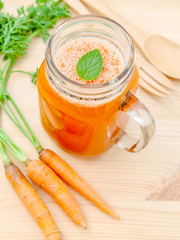Glasses of carrot juice with carrot roots on wooden background.G
