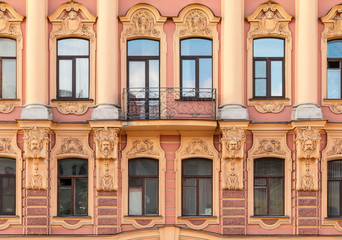 Fototapeta na wymiar Several windows in a row and balcony on facade of urban apartment building front view, St. Petersburg, Russia.