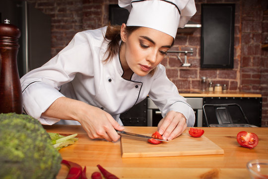 Female chef cook cutting vegetables in the kitchen  preparing a meal from tomatoes and broccoli