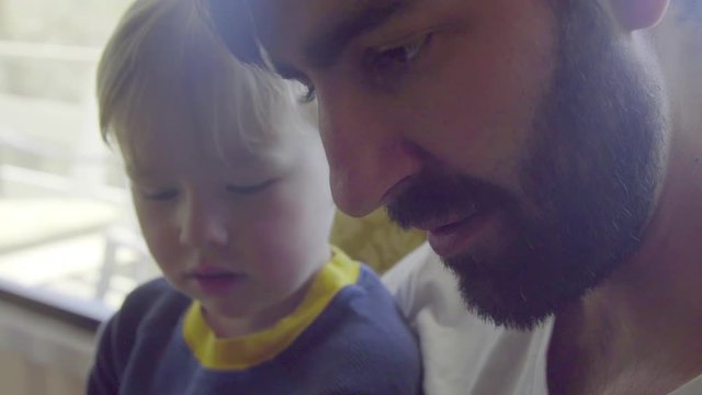 Nephew and uncle look down at a tablet together 