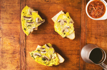 Scrambled eggs with mushrooms on a French baguette slices and coffee for a breakfast