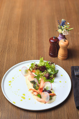 Mixed salad with warm salmon, crispy salted cucumber and cream cheese cream and herbs