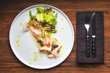 Mixed salad with warm salmon, crispy salted cucumber and cream cheese cream and herbs