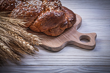 Carving board wheat rye ears sweet bun on wooden background food