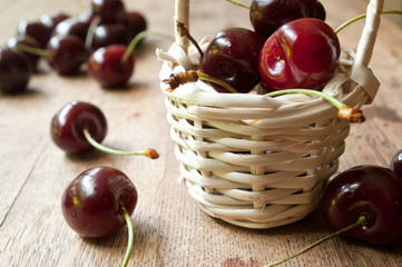 Cerises et petit panier en osier sur table en vieux bois