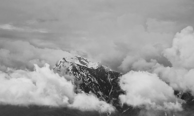 Snowy peak of the mountain shrouded in thick clouds.Black and white