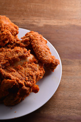 fried chicken on a white plate set on a wood table background