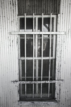 Window with bars and mesh screen on metal building