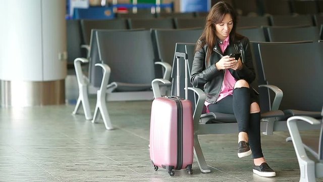 Airline passenger in an airport lounge waiting for flight aircraft. Caucasian woman looking for time in the waiting room