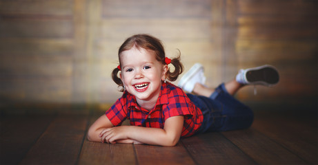 Naklejka premium happy child girl laughing at empty wooden wall