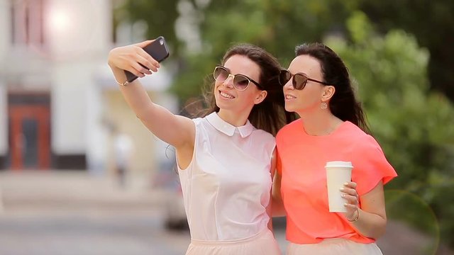 Lifestyle selfie portrait of two young positive woman having fun and making selfie. Concept of friendship and fun with new trends and technology. Best friends saving the moment with modern smartphone