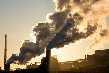 Sunset at steel factory showing smoke chimneys