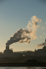 Sunset at steel factory showing smoke chimneys