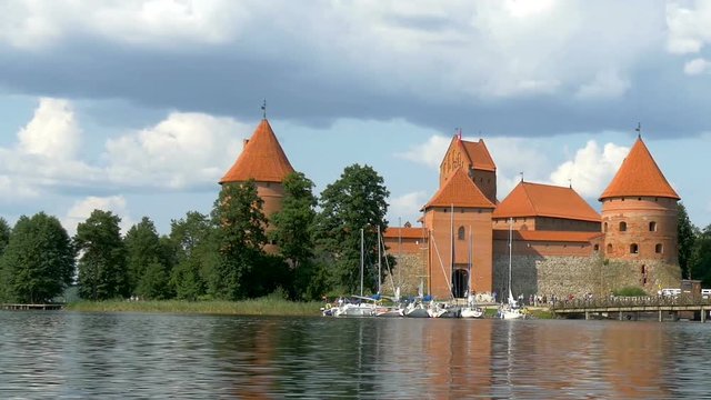 The old red castle on the riverside with the trees on the side of the big lake
