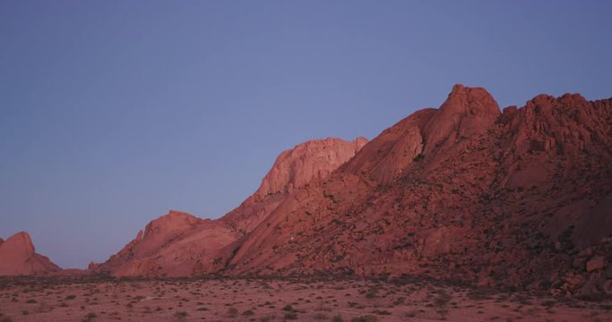 4K panning shot of the moon setting over granite peaks of the Spitzkoppe mountains