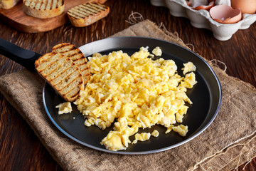 Homemade rustic breakfast Scrambled eggs on Pan with grilled toast.