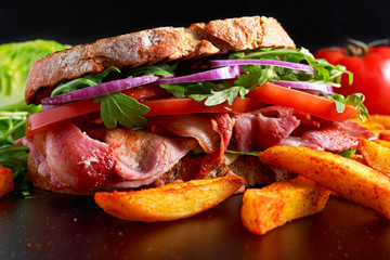 Fresh homemade BLT sandwich on grilled bread with bacon, lettuce, beef tomato, red onions, wild rocket and chips