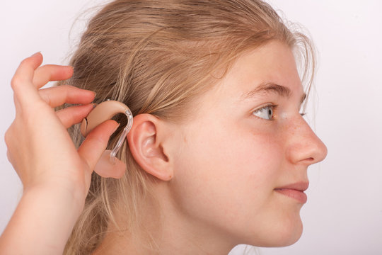 Girl insertin hearing aid into ear
