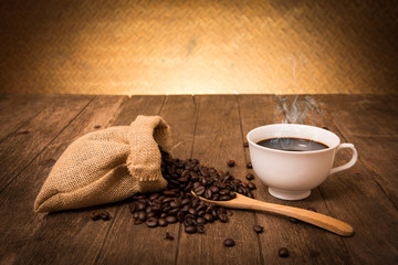 Cup of coffee and coffee beans on sackcloth on wooden with old s
