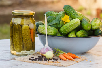 Cucumbers in metal bowl, vegetables and spices for pickling and jar pickled cucumbers
