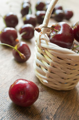 Cerises et petit panier en osier sur table en vieux bois