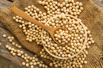 Whole grains Soybean on wooden bowl and spoon putting on linen sack, top view