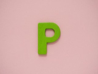 Capital letter P. Green letter P from wood on pink background.