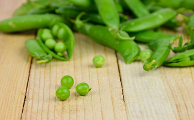 Pods of green peas close-up on wooden background.