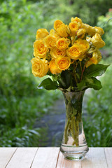 Bunch of yellow roses in a vase. In the garden.