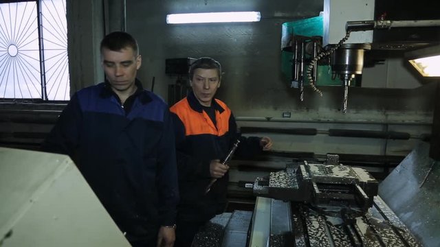 Workers change a drill bit on CNC machine.