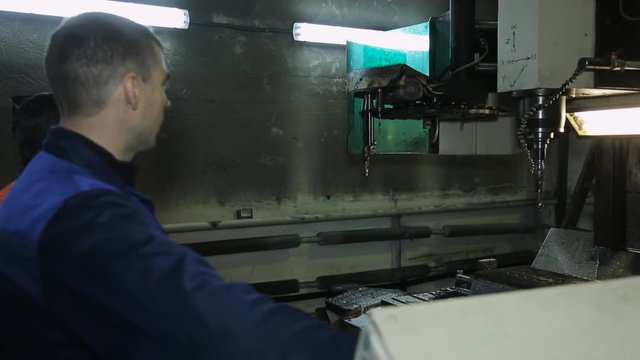 Worker next to machine selects a drill via control panel.