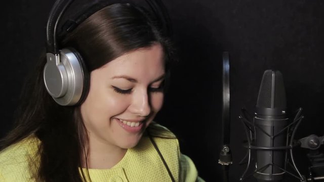 girl in the studio reading a text and sings in the headphones
