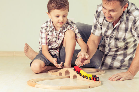 Daddy with little boy playing with toy train on the floor at the