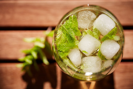 Fresh mint drink with ice in a glass on  a wooden table