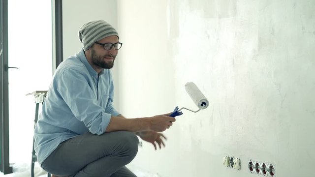 Portrait of young man painting wall at his new home
