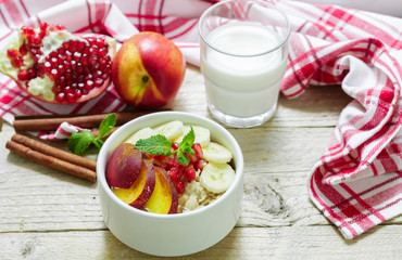 Healthy Breakfast. Oatmeal with banana, peach, nectarine and pomegranate with cinnamon. Selective focus
