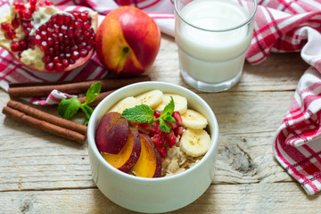 Healthy Breakfast. Oatmeal with banana, peach, nectarine and pomegranate with cinnamon. Selective focus
