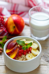 Healthy Breakfast. Oatmeal with banana, peach, nectarine and pomegranate with cinnamon. Selective focus
