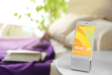 Smart phone with stand on a bedside table in a room