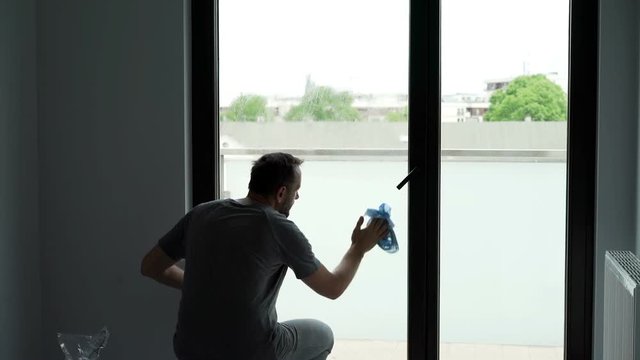 Silhouette of young man cleaning a window at his home

