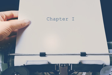 Hand working on an old typewriter with paper, close up