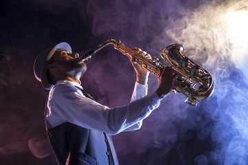 Saxofonista sobre escenario con humo - obrazy, fototapety, plakaty