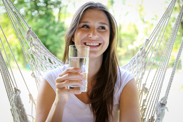 Młoda kobieta pije wodę ze szklanki  - obrazy, fototapety, plakaty