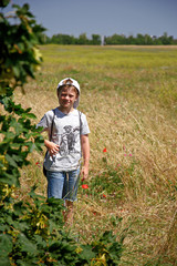 Fototapeta premium Boy walking in a beautiful flower-filled field