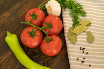 Top view of tomato, garlic, pepper, bay leaf and spices on dark wood background