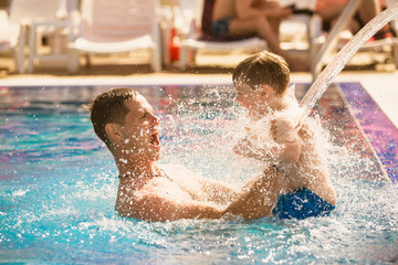 Father playing with son in pool
