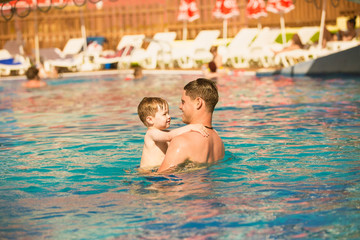 Fototapeta na wymiar Father playing with son in pool