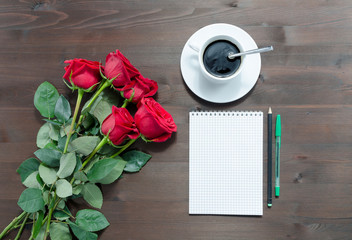 notebook, pens cup of coffee and red roses