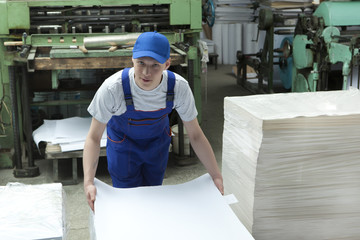  Young man in cap working in print factory